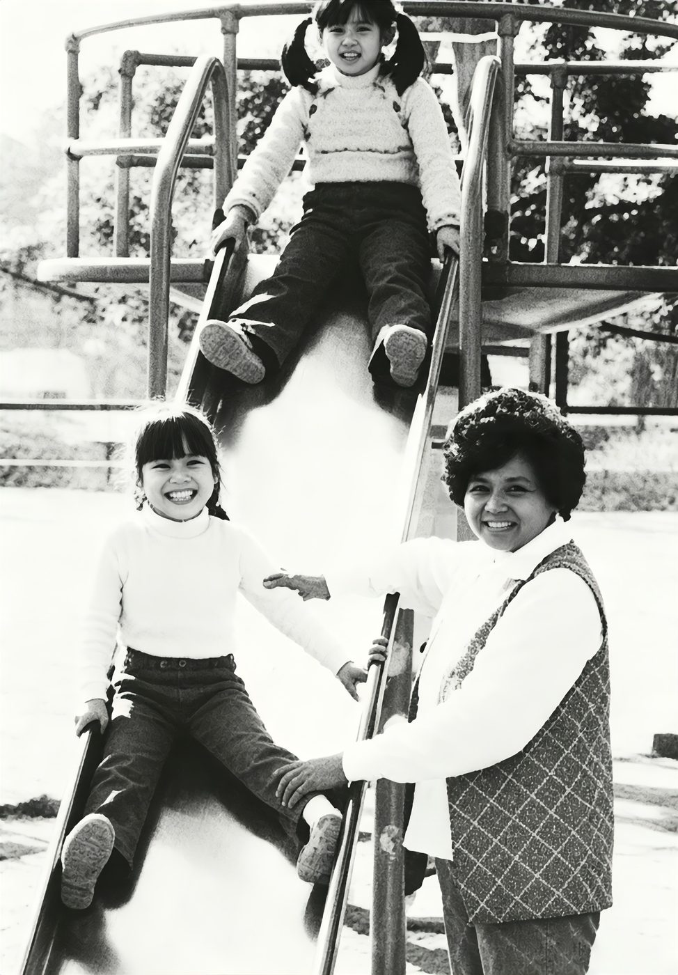 Children on the playground slide with a teacher nearby
