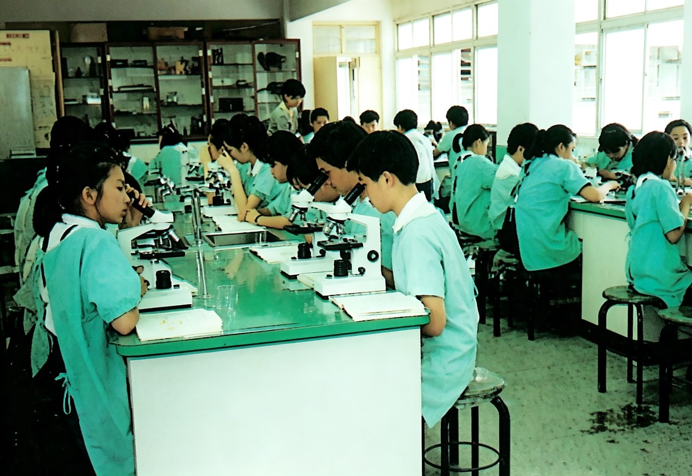 Uniformed students work with microscopes in the science lab