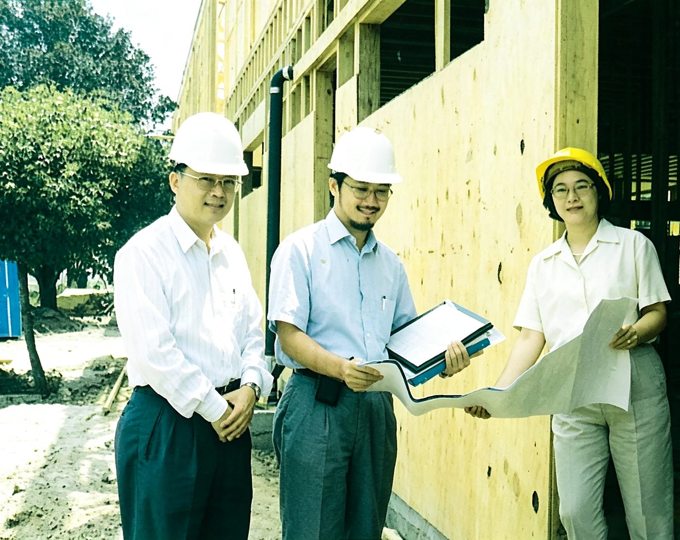 Administrators in hard hats review blueprints during campus construction