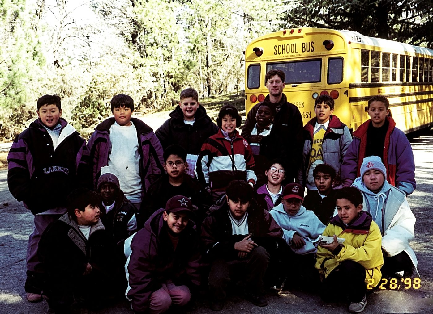 Students pose in front of the yellow school bus before a trip