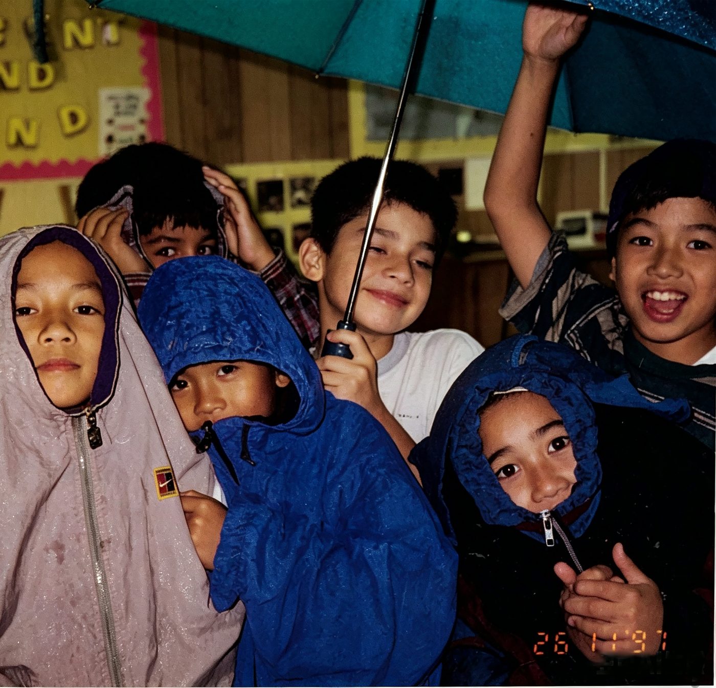 Children under umbrellas and rain hoods on the playground